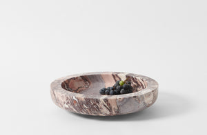 michael verheyden pink taupe and burgundy calcatta viola komm marble bowl shown with a sprig of dark grapes