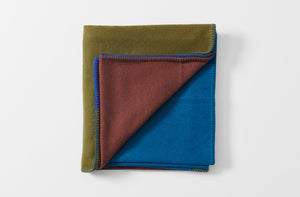 peacock green blue and brown geometric cashmere and wool throw blanket with pig stitch edge shown folded with one corner turned up