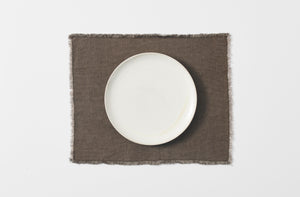 peat hopsack linen placemat with fringe edge shown with a white dinner plate from overhead