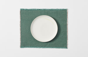 spruce hopsack linen placemat with fringe edge shown from overhead with a white dinner plate