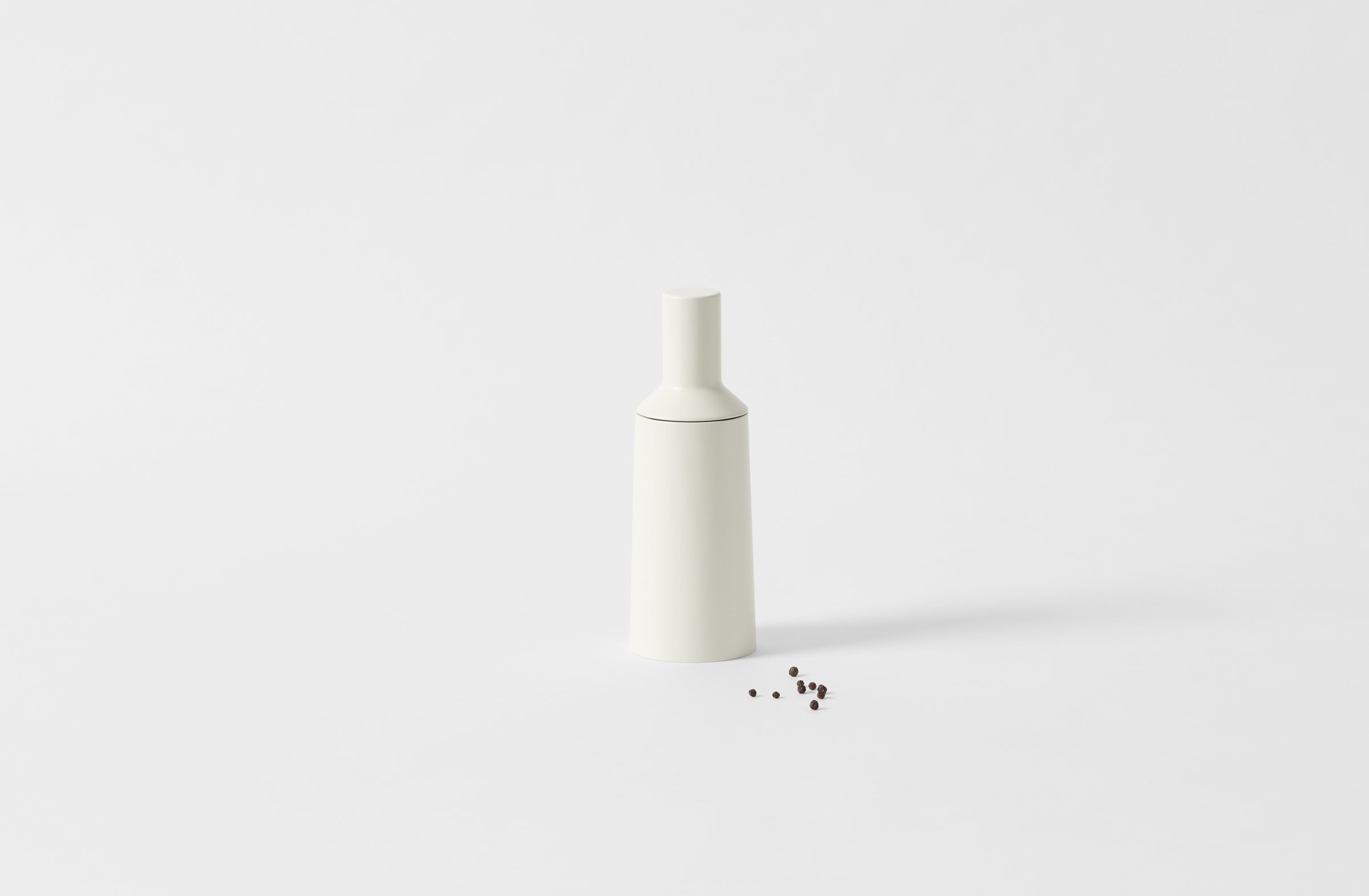 white wood mill shown with peppercorns to one side